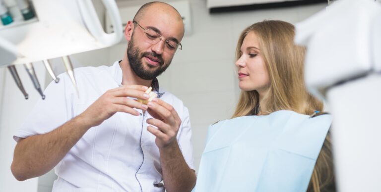 Dentist showing dental jaw to female patient